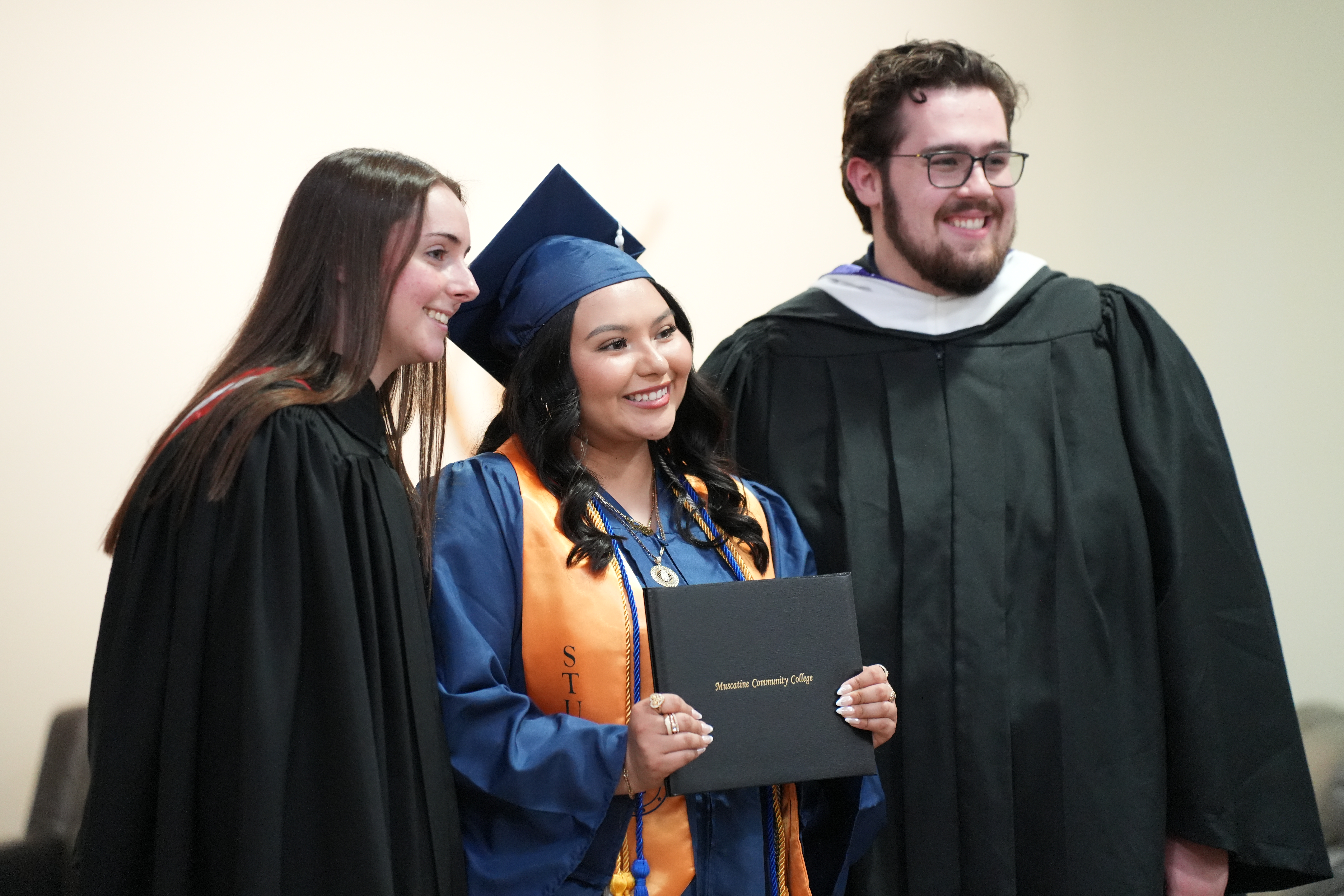 Elexiana Oliva posing for photo with MCC staff after graduation.